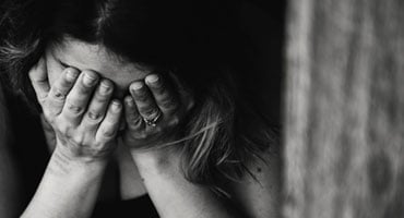 Mujer con el rostro cubierto por las manos mostrando expresión de tristeza o malestar