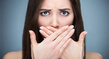Mujer cubriéndose la boca con las manos mostrando gesto de incomodidad
