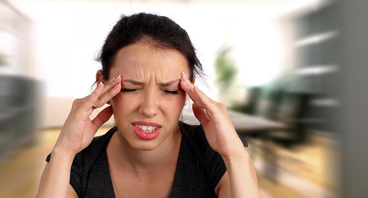 Mujer con las manos en las sienes mostrando gesto de dolor en el rostro