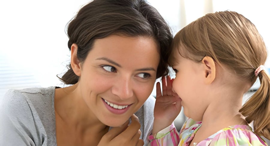 Mujer adulta escuchando a una niña pequeña que le habla al oído