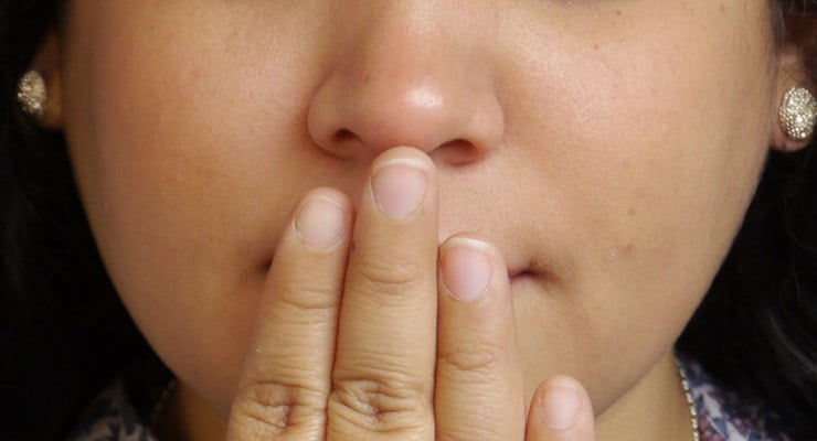 Primer plano del rostro de una mujer con la mano cubriendo la boca