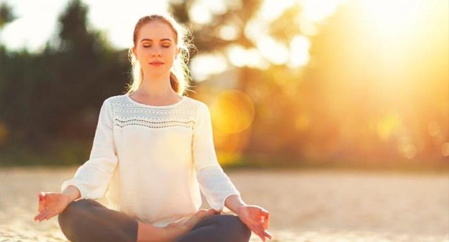 Mujer joven meditando al aire libre durante el atardecer para ilustrar el equilibrio mental y el programa de neuroeducación.