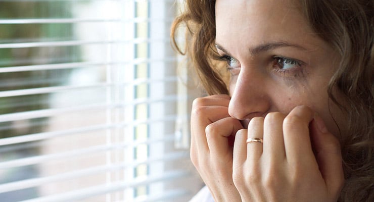 Mujer con expresión de preocupación mirando por una ventana