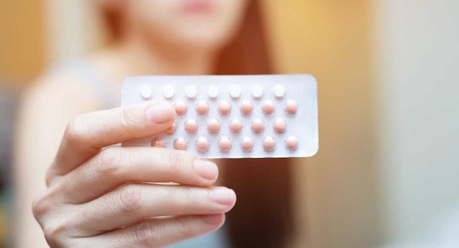 Primer plano de la mano de una mujer sosteniendo un blíster de pastillas anticonceptivas frente a ella, representando la elección de métodos de planificación.