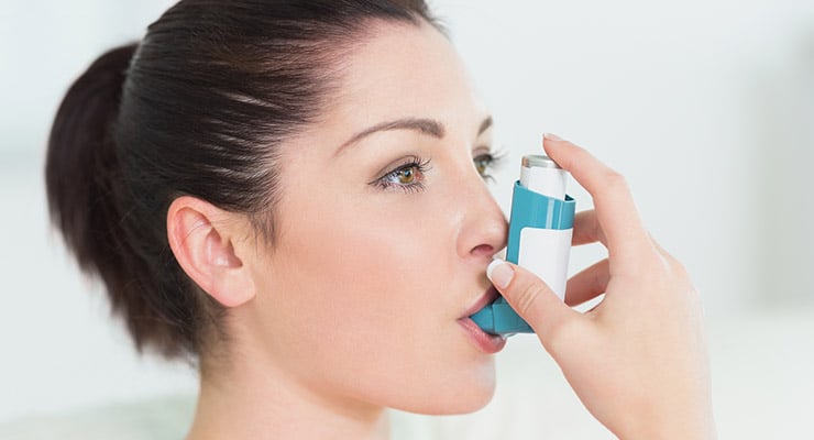Mujer utilizando un inhalador para administrar medicamento por la boca