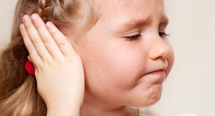 Niña tocándose la oreja con gesto de molestia o dolor