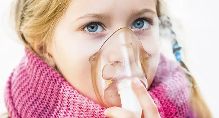 Niña utilizando una mascarilla de inhalación para respirar