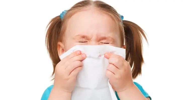 Niña cubriéndose la nariz y la boca con un pañuelo desechable