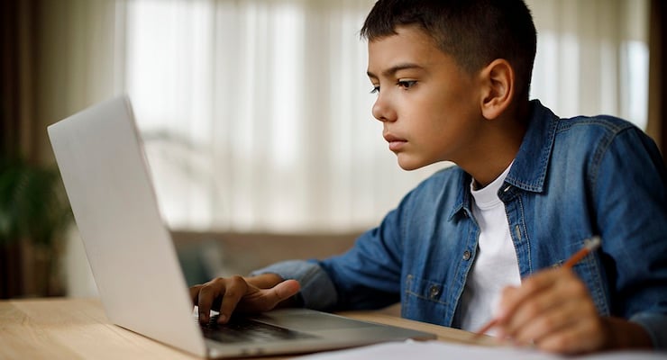 Niño utilizando una computadora portátil mientras estudia en casa