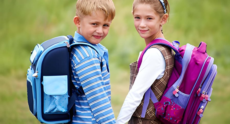 Dos niños de espaldas sonriendo con mochilas escolares en un entorno al aire libre