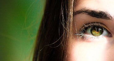 Primer plano del ojo de una mujer con iris color miel, resaltando la importancia de la salud ocular y la protección contra la radiación ultravioleta.