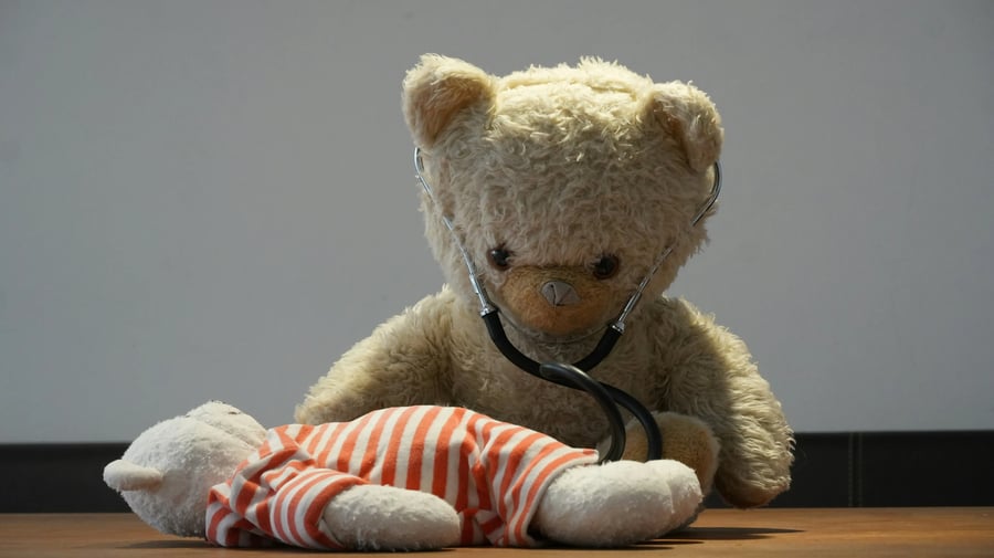 Oso de peluche con estetoscopio revisando a otro peluche en una escena pediátrica