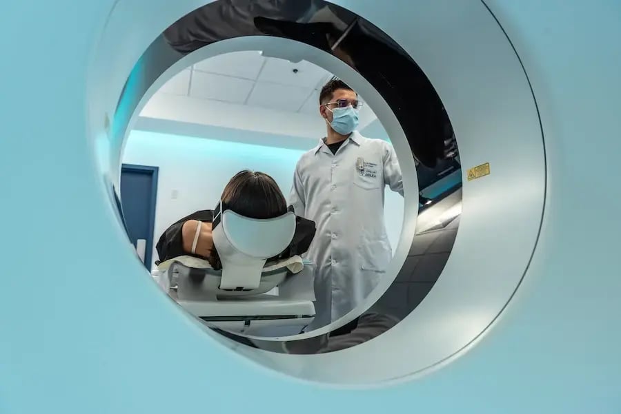Paciente posicionada en tomógrafo mientras un técnico la asiste durante el estudio.