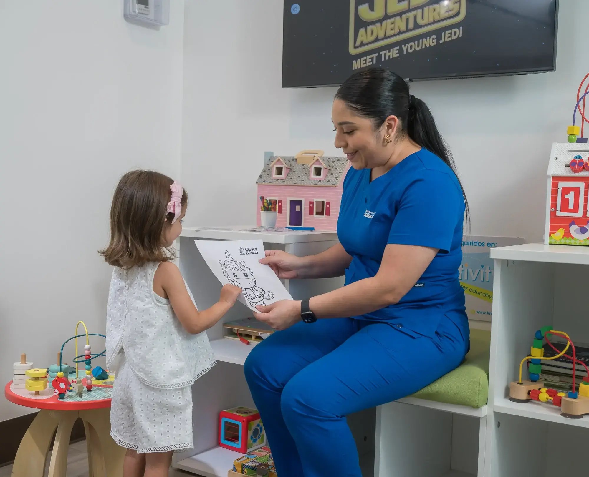 Enfermera entregando material didáctico a niña en área pediátrica de Clínica Bíblica.