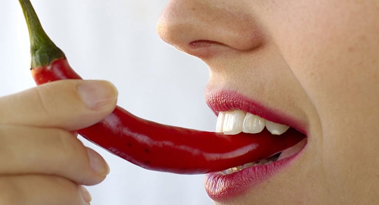 Persona mordiendo un chile rojo