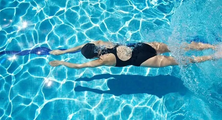 Persona nadando en una piscina con traje de baño y gorro
