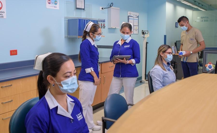 Personal de salud del Hospital Clínica Bíblica trabajando en un área clínica con pacientes.