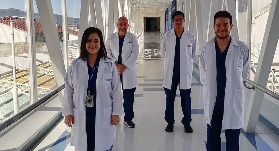 Grupo de profesionales de la salud con batas blancas posando en un pasillo iluminado del hospital