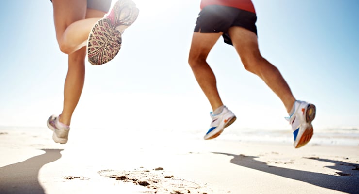 Personas corriendo en la playa con calzado deportivo vistas desde las piernas