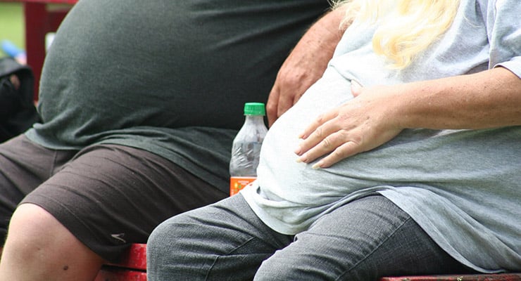 Dos personas sentadas con el abdomen visible en un espacio exterior