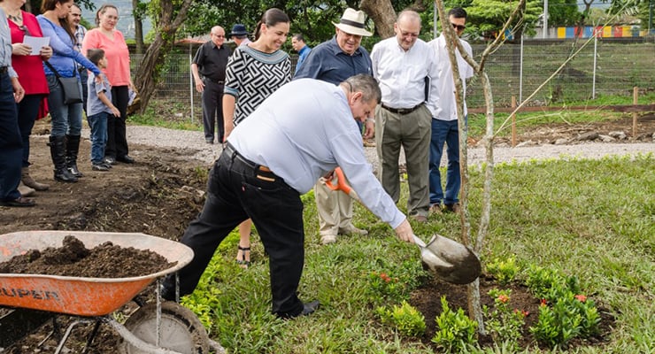 Grupo de personas participando en la siembra de un árbol en un área verde
