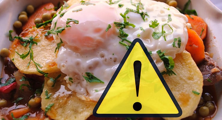 Plato de comida con huevo y verduras que incluye un ícono de advertencia superpuesto