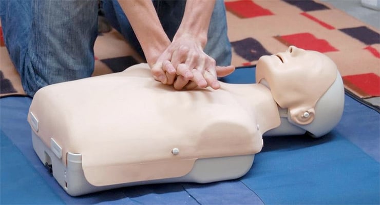 Persona realizando compresiones torácicas en un maniquí durante una práctica de reanimación cardiopulmonar