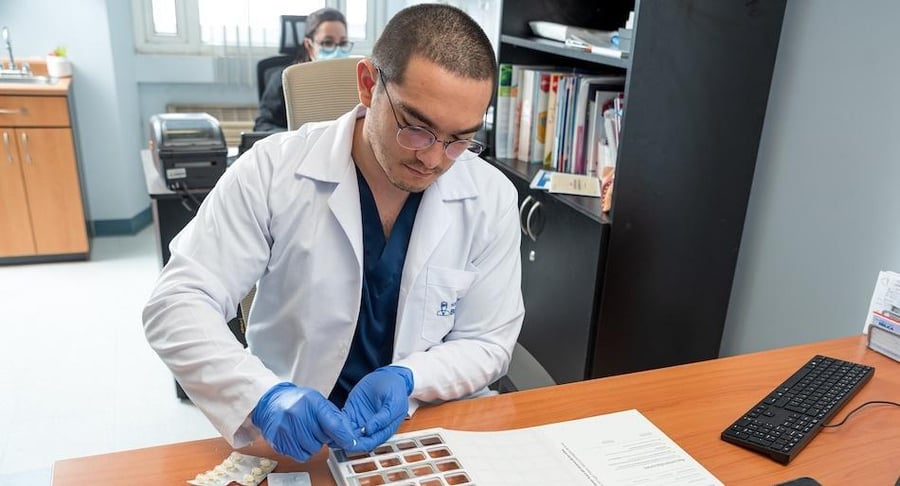 Especialista en farmacia organizando medicamentos en un pastillero para mejorar la adherencia al tratamiento del paciente.
