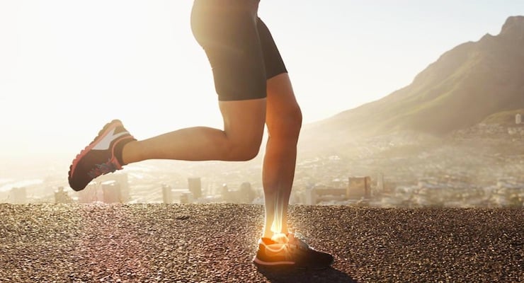 Primer plano de las piernas de un deportista corriendo al aire libre con un efecto visual que resalta la estructura ósea del tobillo y pie.