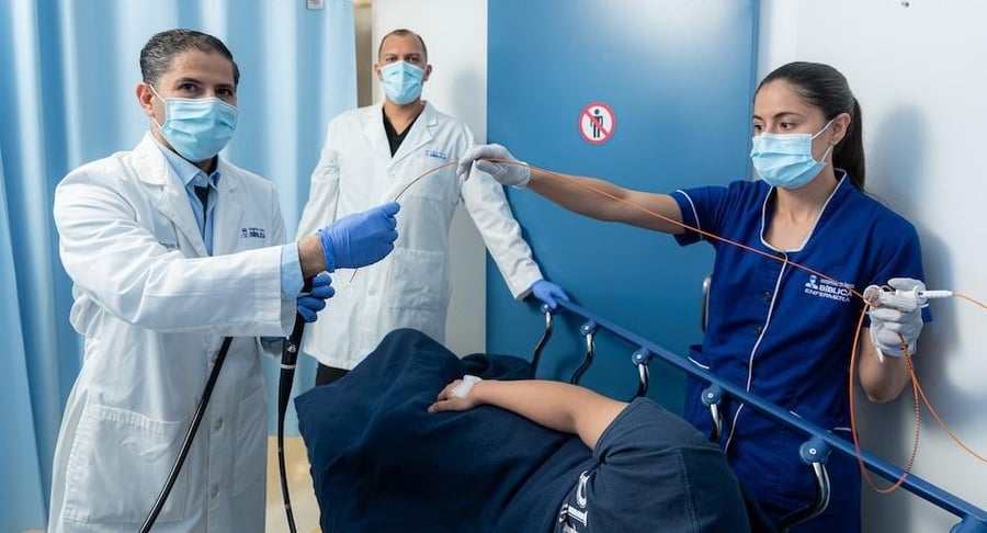 Dr. José Moreno y equipo médico preparando equipo para una colonoscopía preventiva a un paciente en camilla