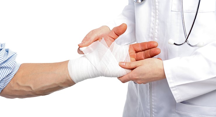 Profesional de la salud colocando una venda en la mano de una persona