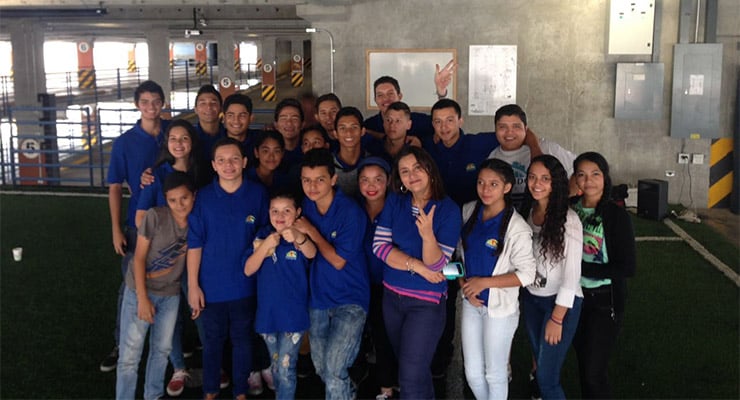Grupo de jóvenes y adultos con camisetas azules posando juntos en un espacio interior