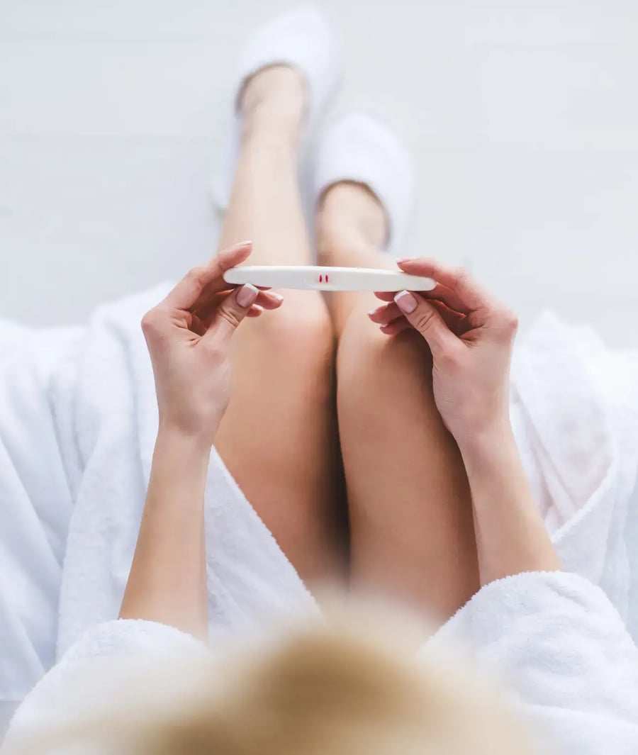 Mujer sosteniendo prueba de embarazo positiva en la Clínica Bíblica.