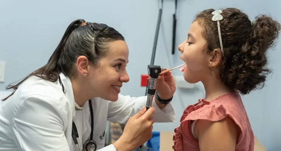 Doctora revisando la garganta de una niña durante consulta médica pediátrica