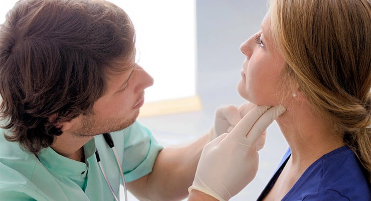 Profesional de la salud examinando el cuello de una paciente durante una revisión médica.