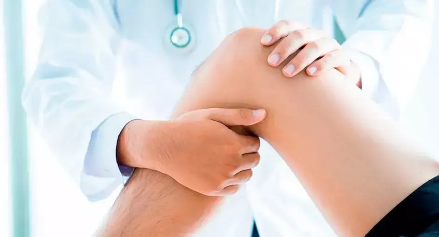 Médico examinando la rodilla de un paciente durante revisión ortopédica