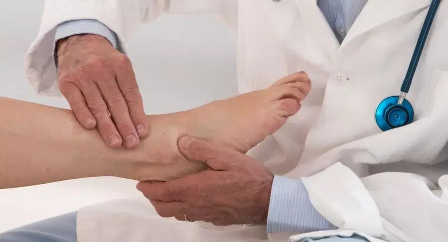 Médico revisando el tobillo de un paciente durante consulta ortopédica