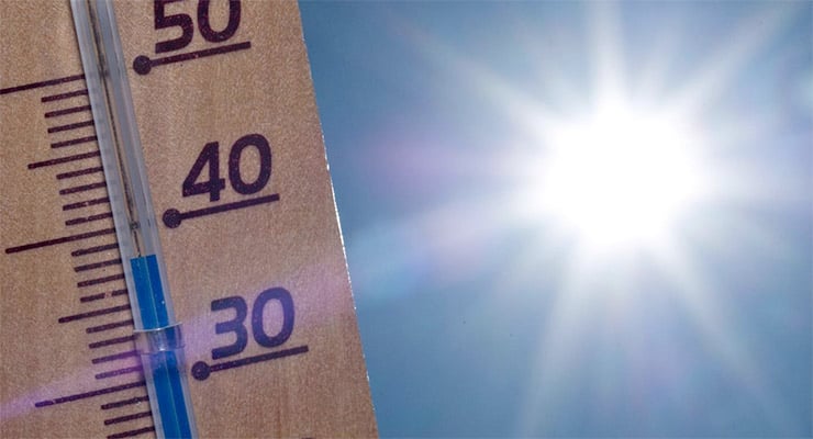 Termómetro marcando alta temperatura con el sol brillante al fondo en el cielo.