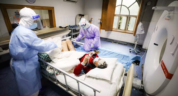 Personal médico con equipo de protección atendiendo paciente hospitalizado por COVID-19