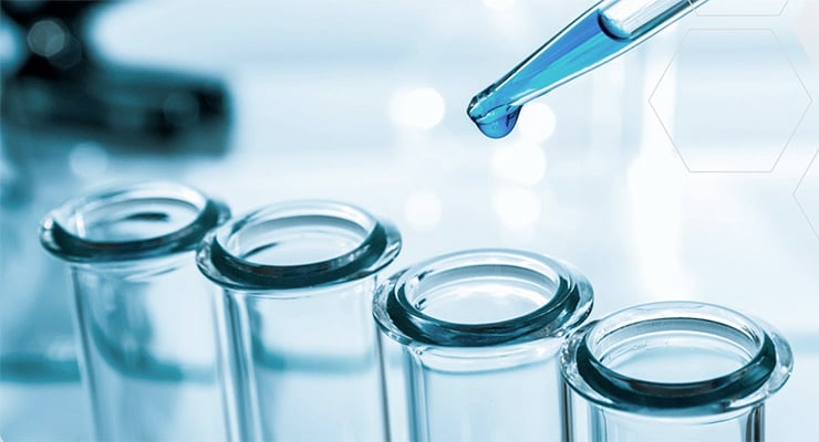 Tubos de ensayo de laboratorio con pipeta depositando una gota de líquido.