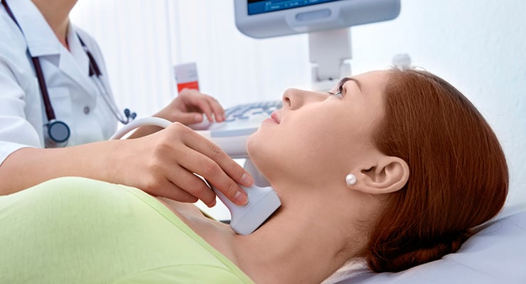 Profesional de la salud realizando un ultrasonido en el cuello de una mujer