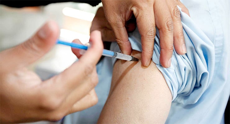 Aplicación de vacuna en el brazo de una persona por personal de salud