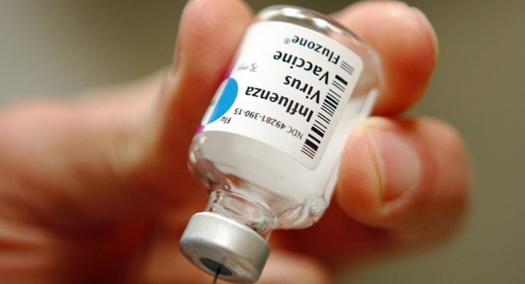 Mano sosteniendo un frasco de la vacuna Fluzone contra el virus de la influenza para la campaña de vacunación estacional.