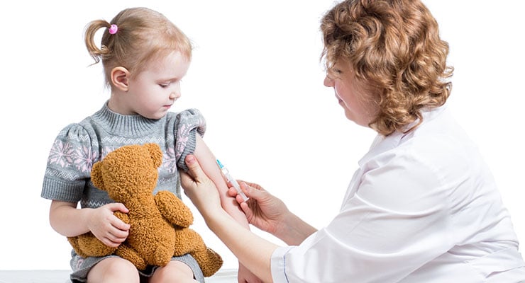 Profesional de salud aplicando una vacuna en el brazo de una niña pequeña sentada