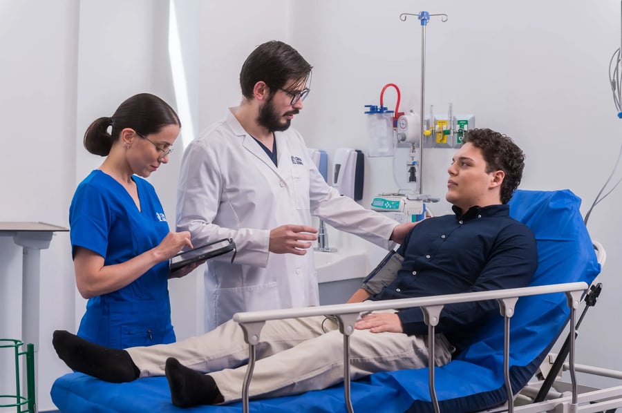 Doctor y enfermera atienden a paciente en cama hospitalaria durante valoración médica