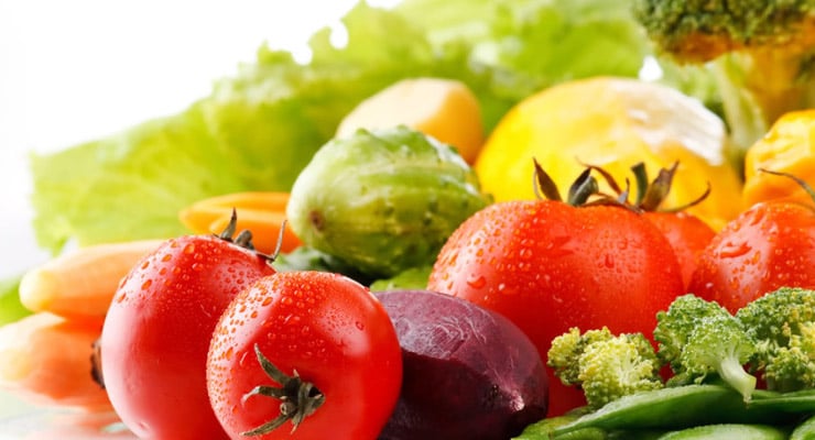 Vegetales frescos como tomates, brócoli, zanahoria y lechuga sobre fondo claro