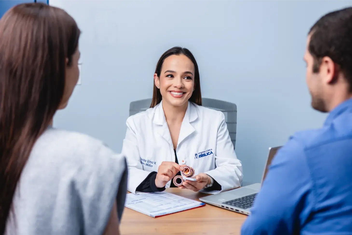 Doctora explicando diagnóstico médico a pareja durante una consulta