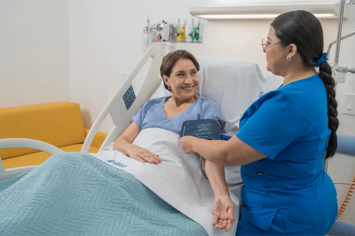 Enfermera midiendo la presión arterial a paciente hospitalizada sonriente