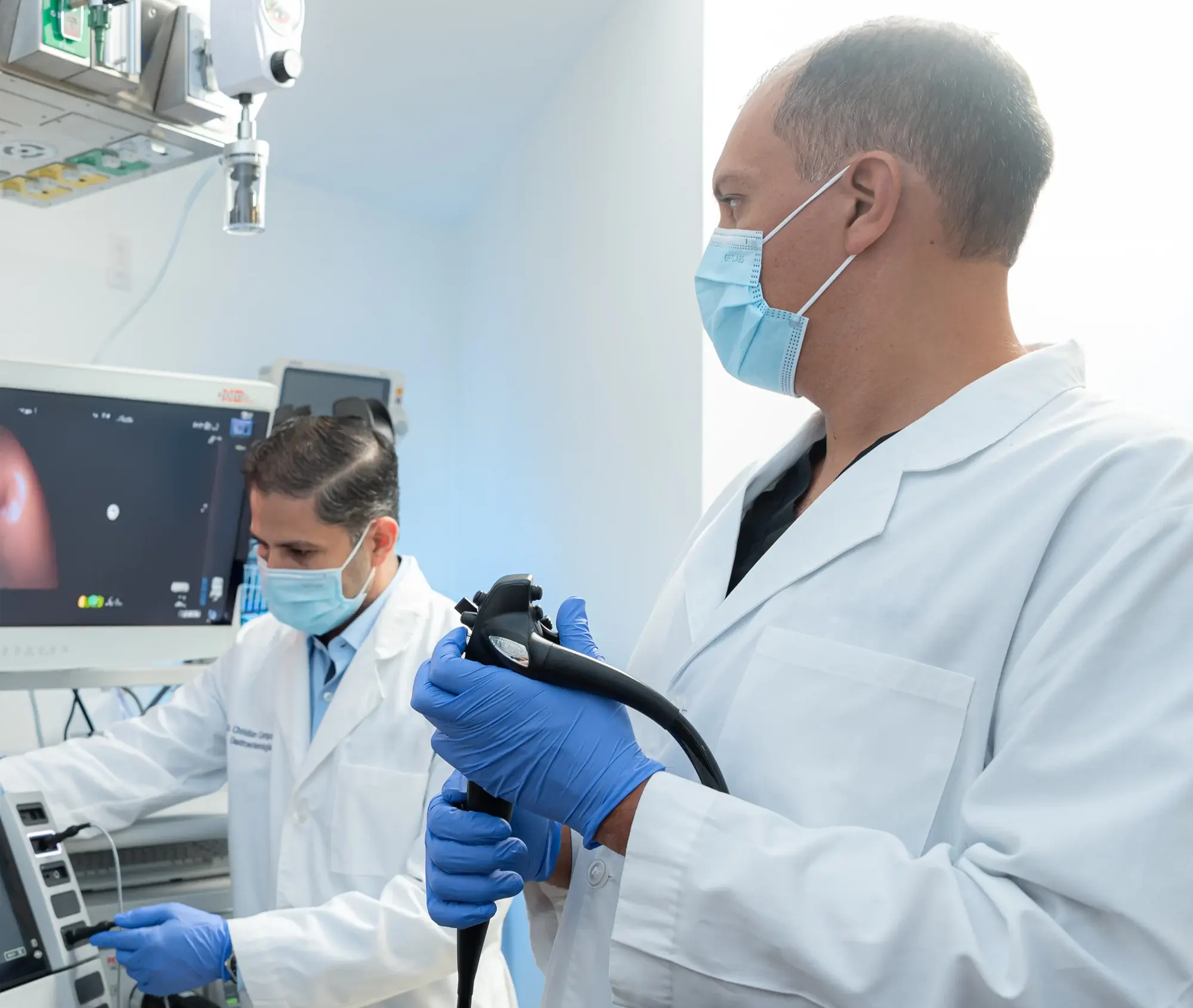 Médicos con mascarilla realizando procedimiento endoscópico con equipo especializado.