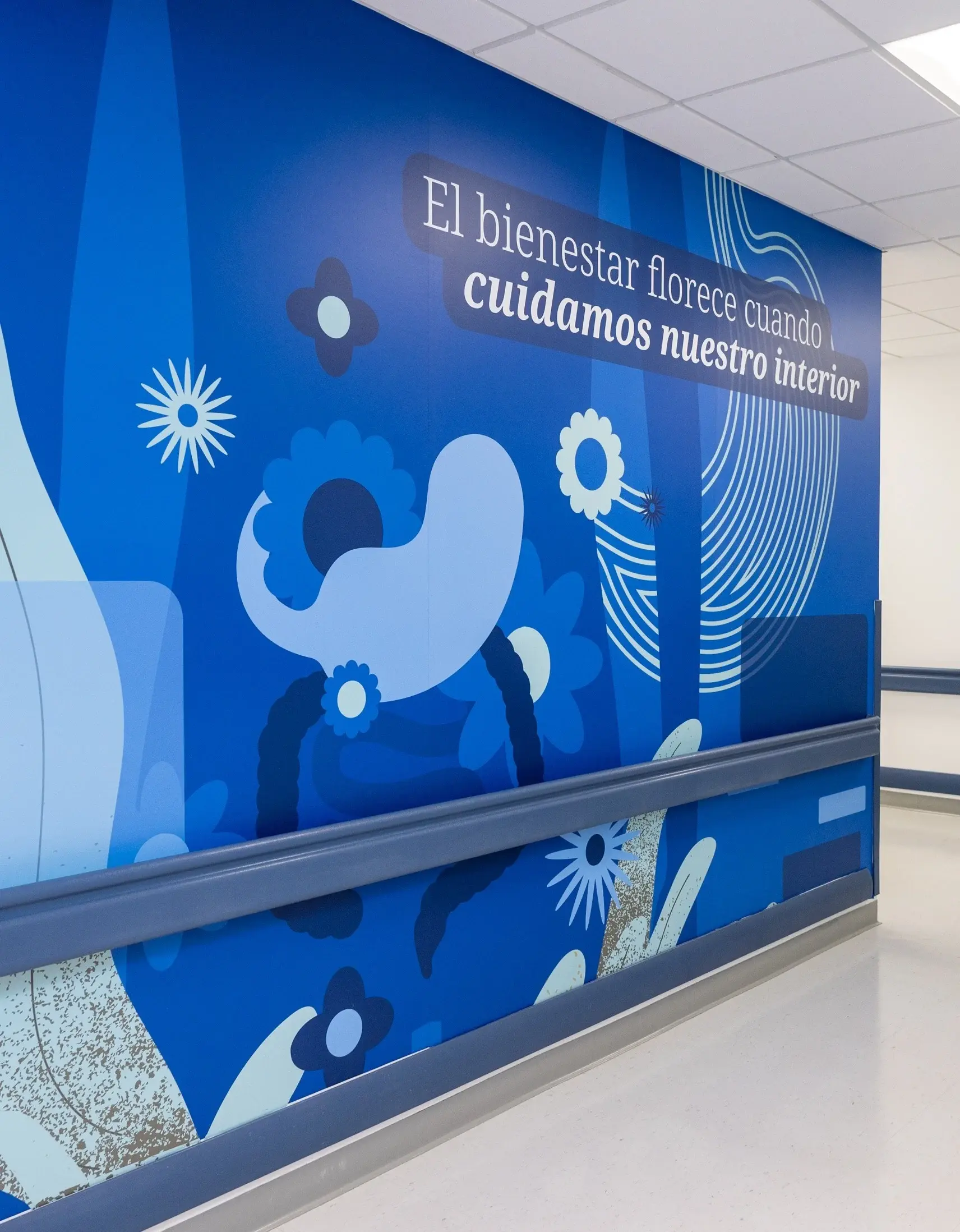 Mural azul con mensaje sobre bienestar y cuidado interior en pasillo de hospital.